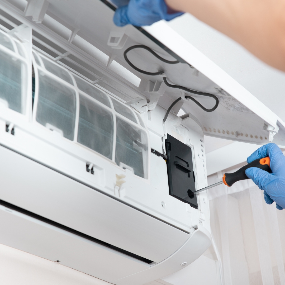 man working on an AC unit with a screw driver